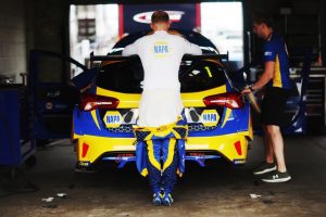 Sutton stands behind his Ford Focus ST in NAPA Racing UK overalls.
