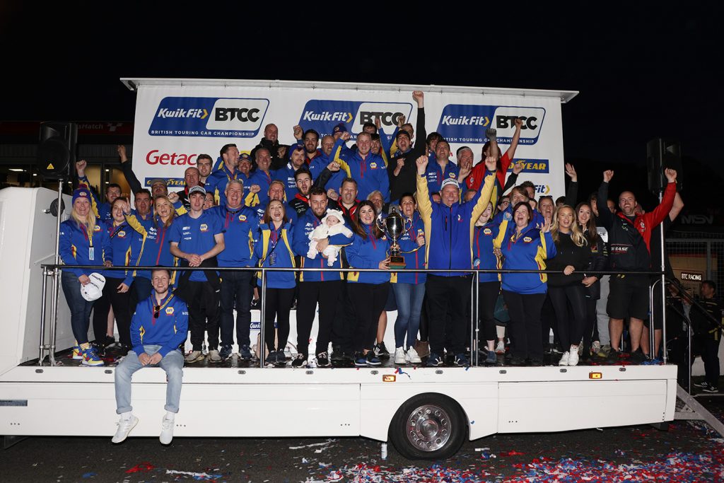 The NAPA Racing UK team crowds the podium to celebrate their BTCC Teams' Championship win.