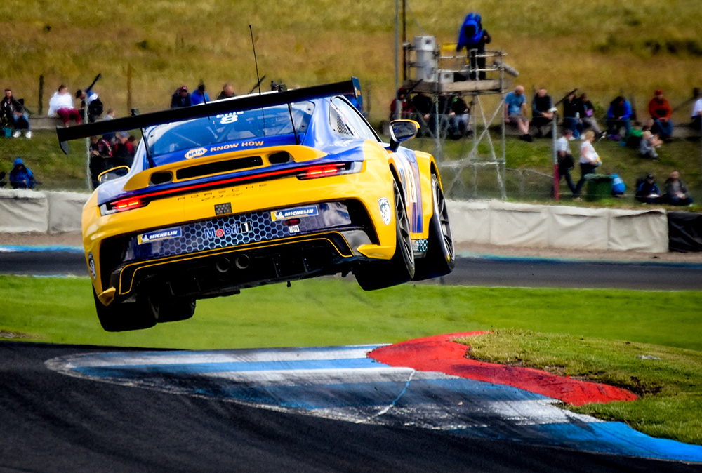 Hugo Ellis lifts all 4 wheels off the track as he navigates a bend in the Porsche Carrera Cup GB.